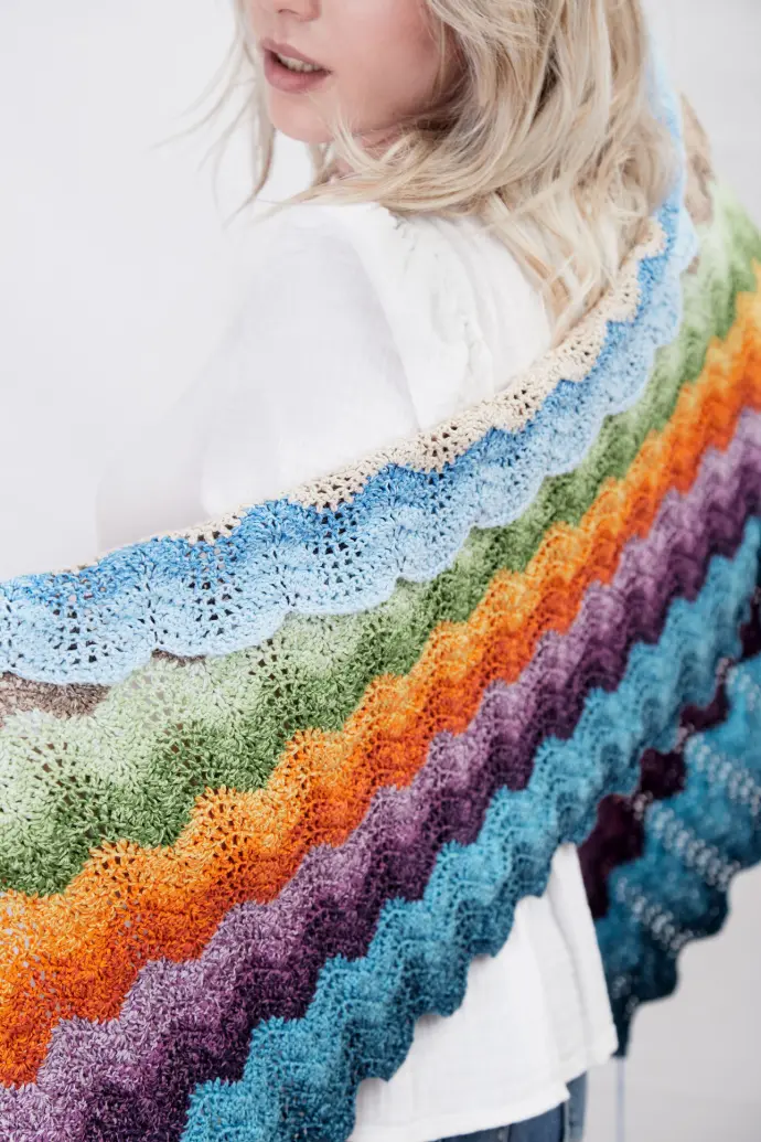 Buntes, gehäkeltes Deckenmuster mit wellenförmigen, muschelförmigen Stichen in pastellfarbenen und kräftigen Tönen, handgefertigte Detailstruktur.